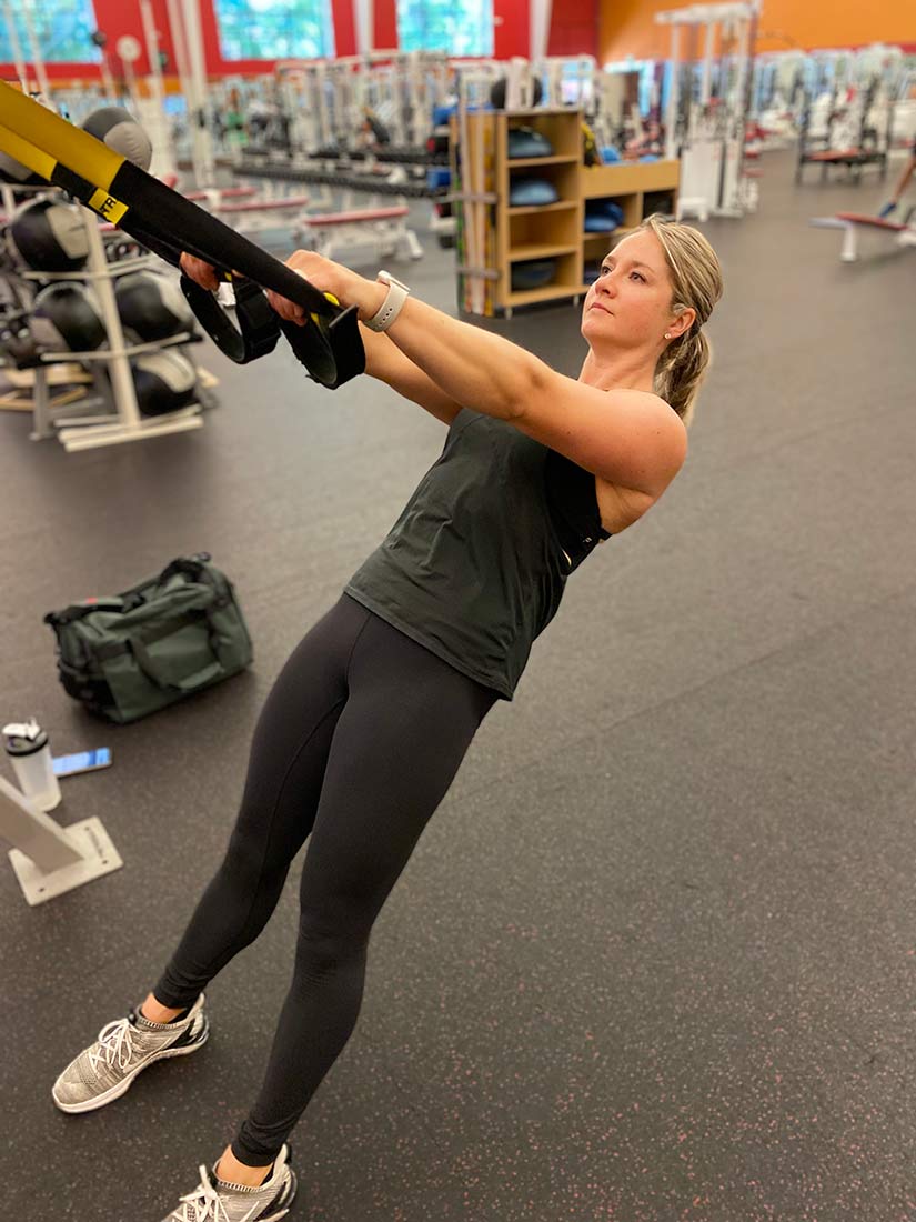Woman performing a trainer row on a suspension cable.